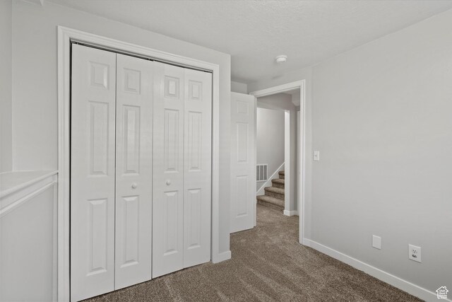 2124 N 2525 W, Clinton, UT 84015 - unfurnished bedroom with a closet, baseboards, visible vents, a textured ceiling, and carpet flooring