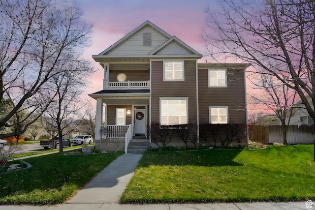 view of front of house with a yard, fence, covered porch, and a balcony