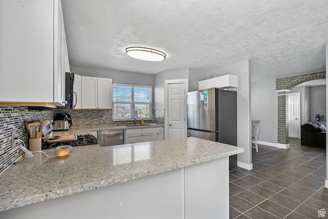 1468 N 220 W, Tooele, UT 84074 - kitchen featuring a peninsula, white cabinets, appliances with stainless steel finishes, a sink, and backsplash