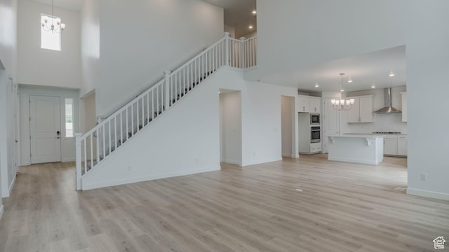876 W Sika Cir S Unit 205, Saratoga Springs, UT 84045 - unfurnished living room featuring a chandelier, a towering ceiling, stairs, light wood finished floors, and recessed lighting
