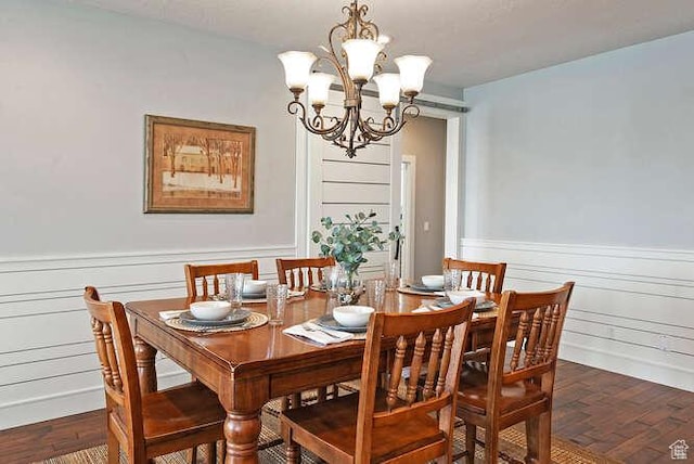 dining space featuring a chandelier, wainscoting, and dark wood-style floors