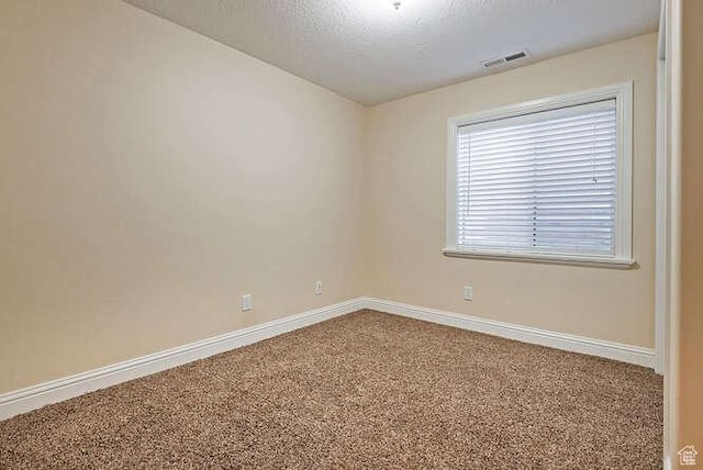 carpeted empty room with visible vents, baseboards, and a textured ceiling