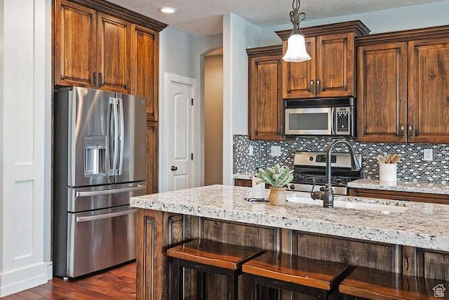 kitchen with light stone counters, backsplash, and stainless steel appliances