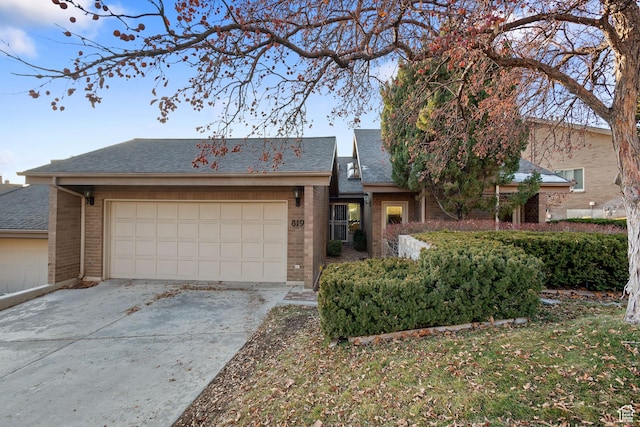 819 N Juniperpoint Dr, Salt Lake City, UT 84103 - view of front facade featuring a shingled roof, brick siding, driveway, and an attached garage