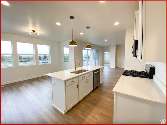 kitchen with light wood-style floors, gas range, a sink, light countertops, and open floor plan