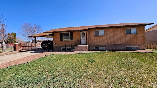 view of front of property with fence, concrete driveway, brick siding, a front lawn, and an attached carport