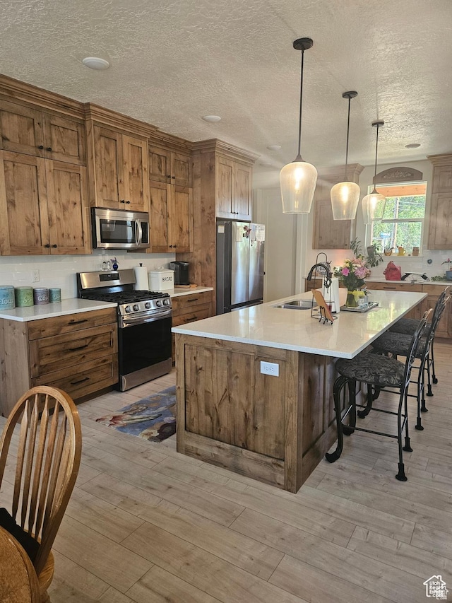 2345 E Cherry Ln, Layton, UT 84040 - kitchen with light wood finished floors, a sink, brown cabinetry, and appliances with stainless steel finishes