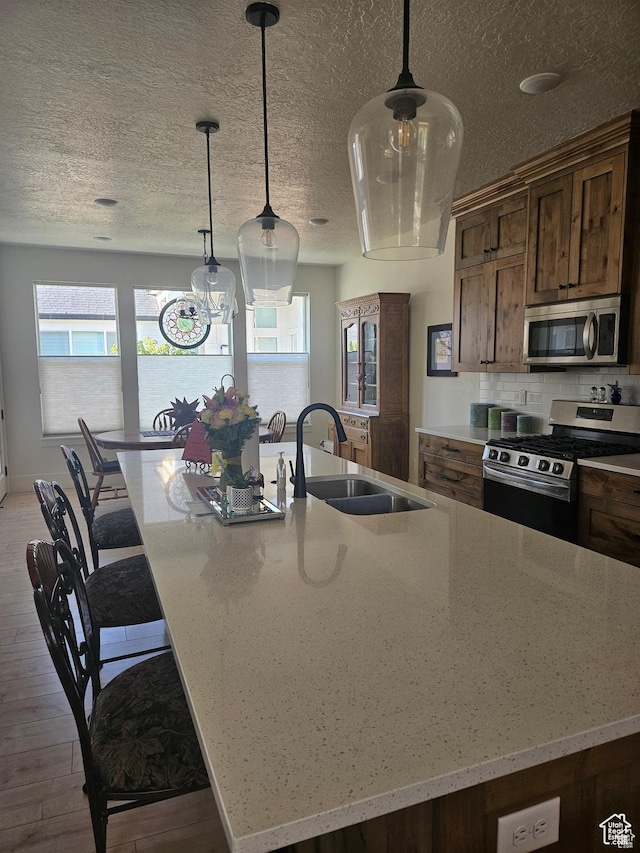 2345 E Cherry Ln, Layton, UT 84040 - kitchen featuring pendant lighting, light wood-type flooring, a large island, a sink, and stainless steel appliances