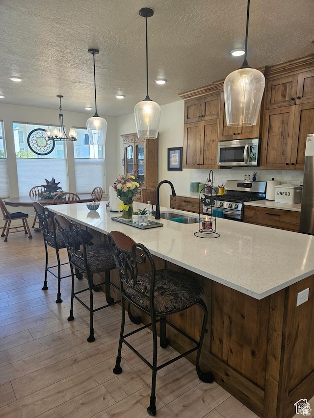 2345 E Cherry Ln, Layton, UT 84040 - kitchen featuring pendant lighting, light wood-type flooring, a sink, and appliances with stainless steel finishes