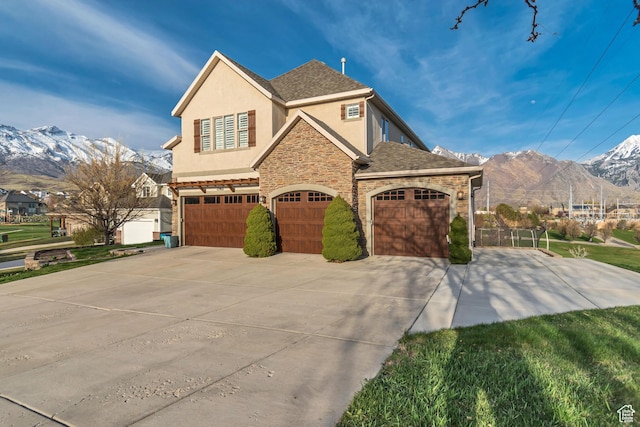 11968 N Ithica Dr, Highland, UT 84003 - view of front of property featuring a mountain view, stone siding, a garage, concrete driveway, and stucco siding