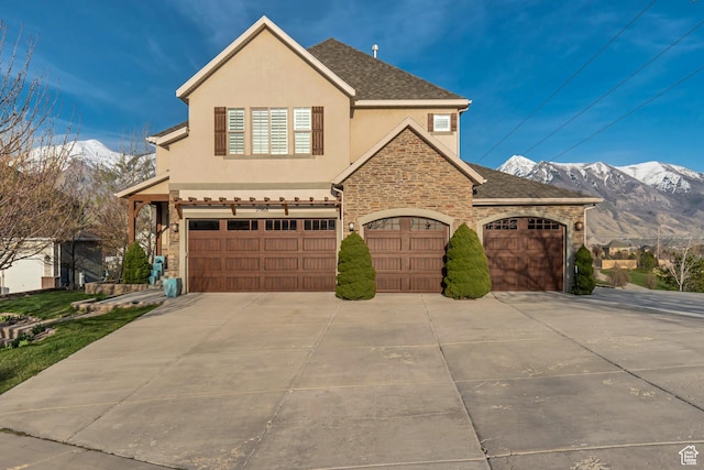11968 N Ithica Dr, Highland, UT 84003 - view of front of property featuring concrete driveway, a mountain view, stucco siding, and stone siding