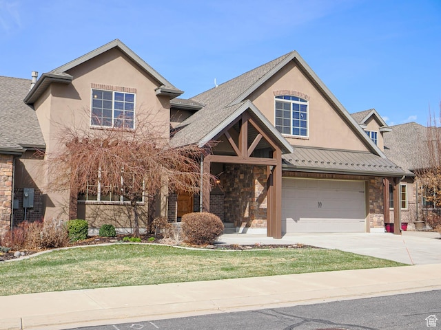 traditional home featuring a front yard, an attached garage, stone siding, concrete driveway, and stucco siding