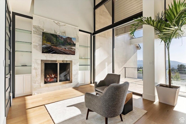 1449 S Devonshire Dr, Salt Lake City, UT 84108 - living area featuring a wall of windows, a towering ceiling, a premium fireplace, and wood finished floors