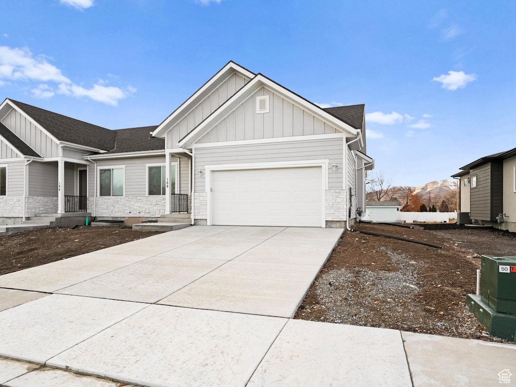 view of front of house featuring an attached garage, board and batten siding, concrete driveway, and stone siding