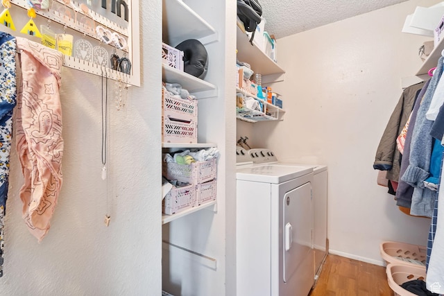 clothes washing area featuring laundry area, independent washer and dryer, a textured ceiling, light wood-style flooring, and baseboards