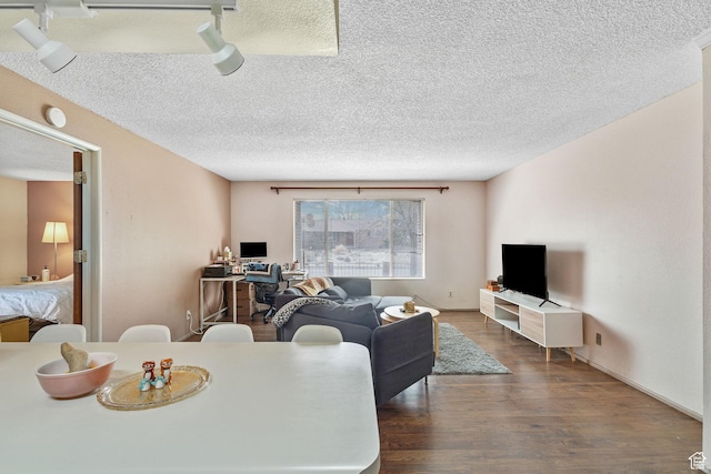 living room with dark wood-type flooring, a textured ceiling, and baseboards