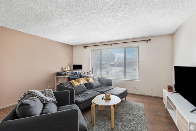 living room with a textured ceiling, baseboards, and wood finished floors