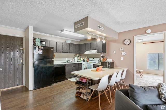 kitchen with a peninsula, under cabinet range hood, visible vents, and black appliances
