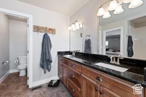 8836 W 3200 S, Cedar City, UT 84720 - bathroom featuring a notable chandelier, baseboards, double vanity, toilet, and a sink