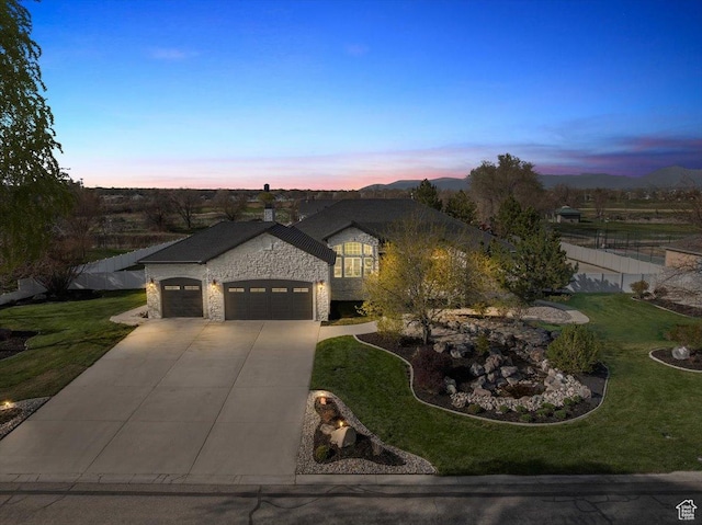 1178 W 13040 S, Riverton, UT 84065 - view of front of house featuring a lawn, driveway, stone siding, an attached garage, and fence