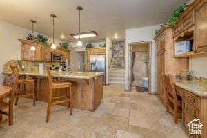 565 S Vasels Rd E Unit 6G, Brian Head, UT 84719 - kitchen with appliances with stainless steel finishes, stone finish floor, a peninsula, brown cabinets, and a breakfast bar area