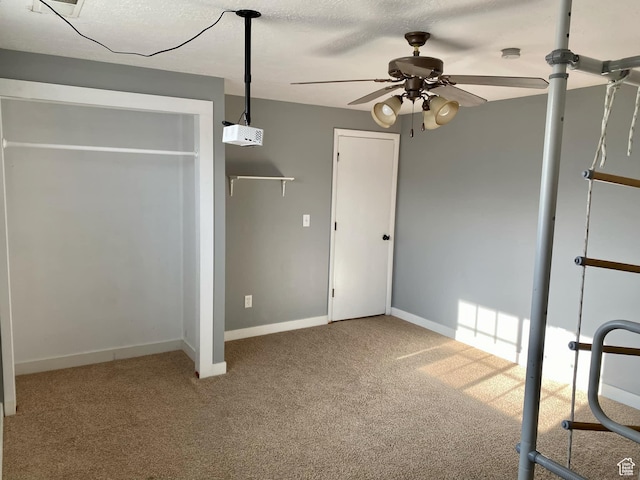 unfurnished bedroom featuring carpet flooring, baseboards, a textured ceiling, and a ceiling fan