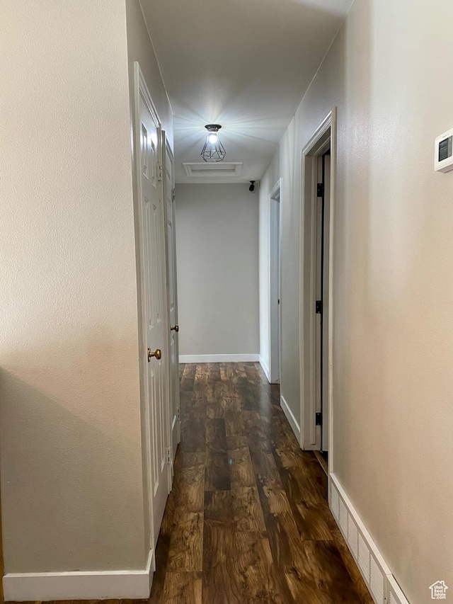 corridor featuring baseboards and dark wood finished floors