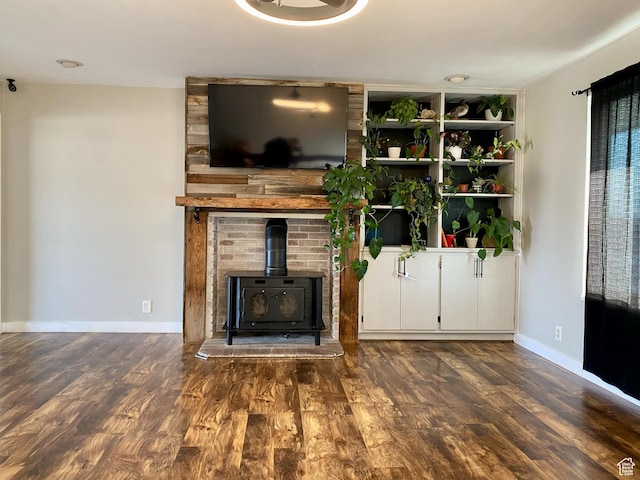 unfurnished living room featuring wood finished floors, a wood stove, and baseboards