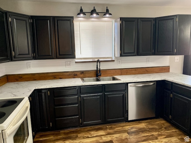 kitchen with light stone counters, dark wood-type flooring, dark cabinetry, dishwasher, and a sink