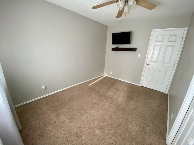 unfurnished room with baseboards, dark carpet, and ceiling fan