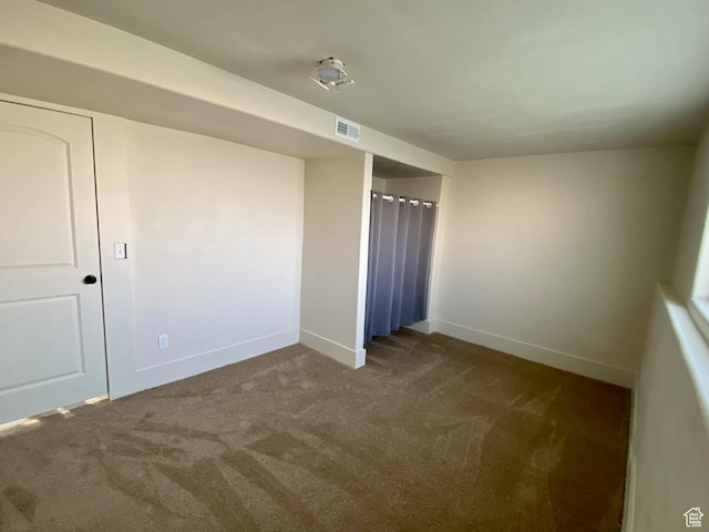 unfurnished bedroom with dark colored carpet, visible vents, and baseboards