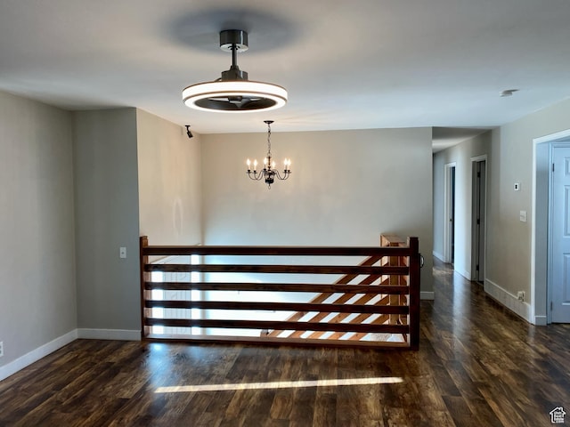 staircase featuring baseboards, a chandelier, and wood finished floors