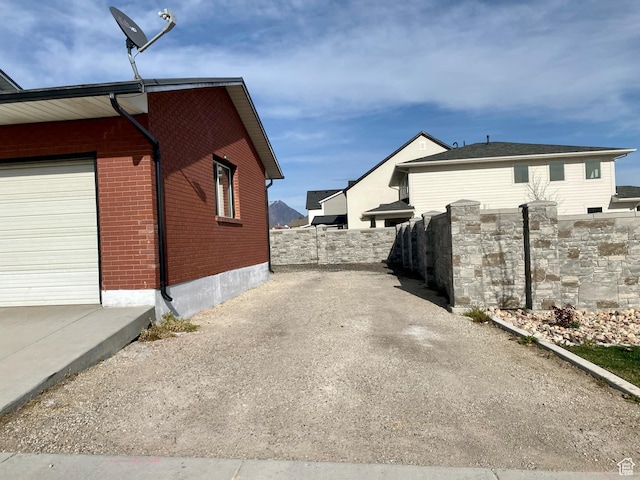 view of home's exterior with brick siding, driveway, fence, and a garage