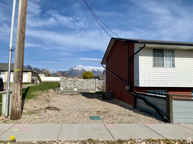view of side of home with a mountain view, fence, and brick siding