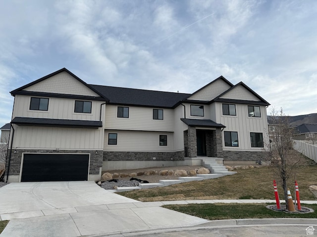 modern farmhouse style home featuring driveway, stone siding, board and batten siding, an attached garage, and fence