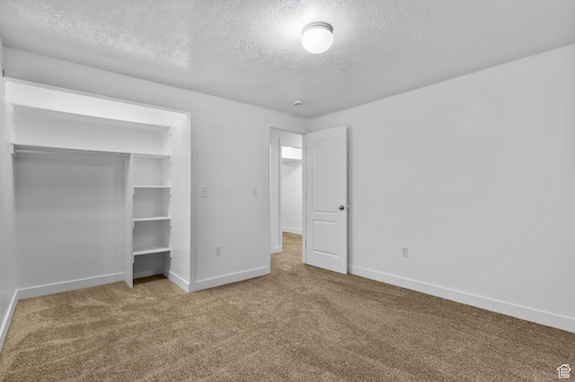 unfurnished bedroom featuring baseboards, carpet, a textured ceiling, and a closet