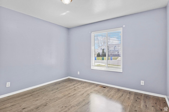empty room with visible vents, baseboards, and wood finished floors