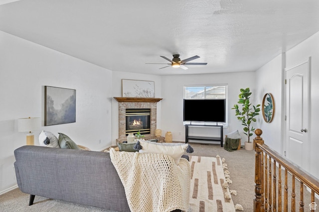 carpeted living area featuring a glass covered fireplace, baseboards, and a ceiling fan