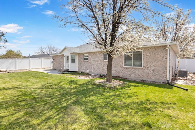 rear view of house with brick siding, a fenced backyard, a patio area, and central AC unit
