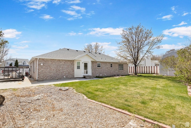 rear view of house with fence, a patio, brick siding, entry steps, and a yard