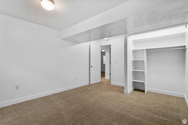 unfurnished bedroom featuring baseboards, a textured ceiling, carpet, and a closet