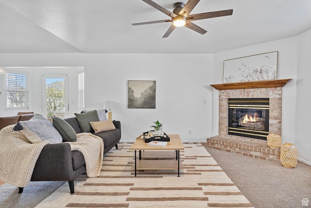 carpeted living area featuring ceiling fan and a fireplace