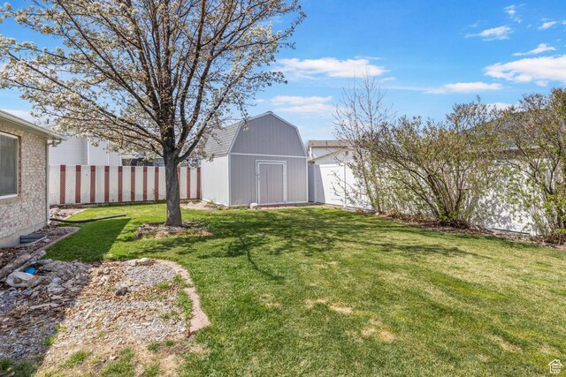 view of yard with an outdoor structure, fence, and a storage shed
