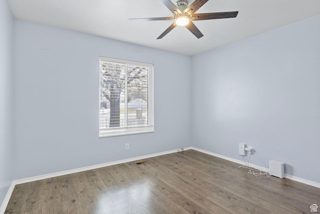 spare room with baseboards, a ceiling fan, wood finished floors, and visible vents