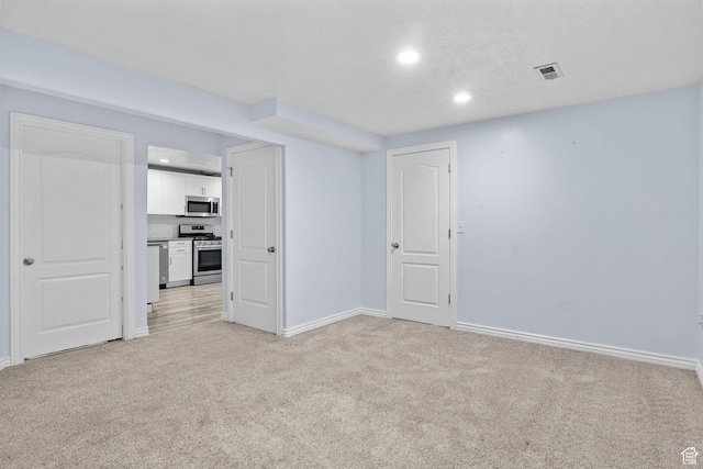 spare room featuring baseboards, light carpet, recessed lighting, and visible vents