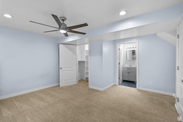 unfurnished bedroom featuring carpet floors, recessed lighting, baseboards, and a walk in closet