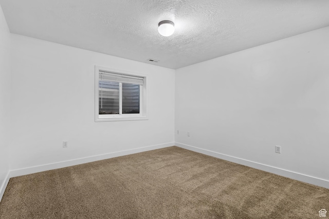 unfurnished room with carpet floors, a textured ceiling, visible vents, and baseboards