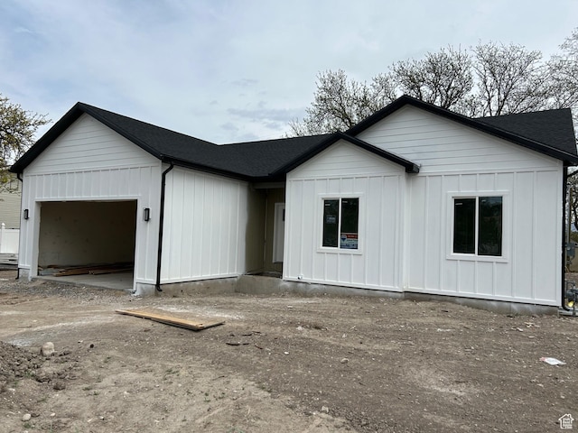view of front of house with a garage, board and batten siding, and roof with shingles