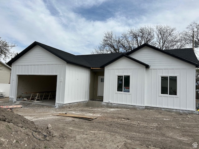 view of front facade with a garage, board and batten siding, and roof with shingles