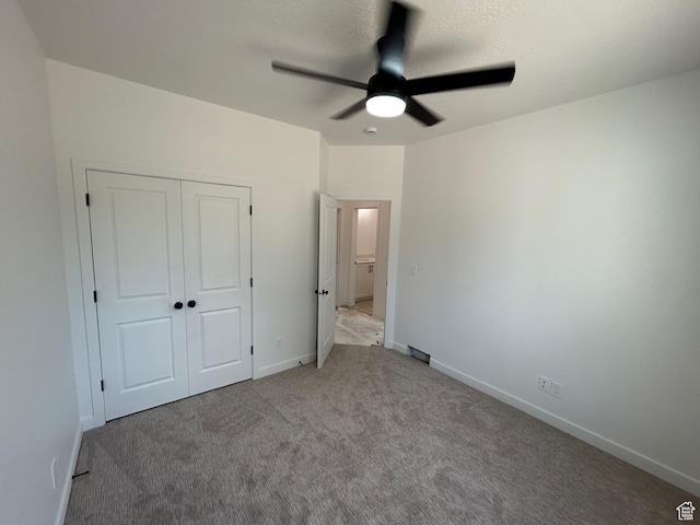 unfurnished bedroom with carpet flooring, baseboards, a closet, and ceiling fan